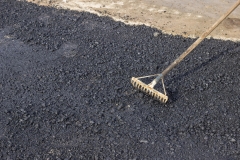 Using a rake to level asphalt pavement